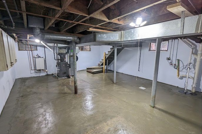After: the same basement with white-lined walls and a sealed floor