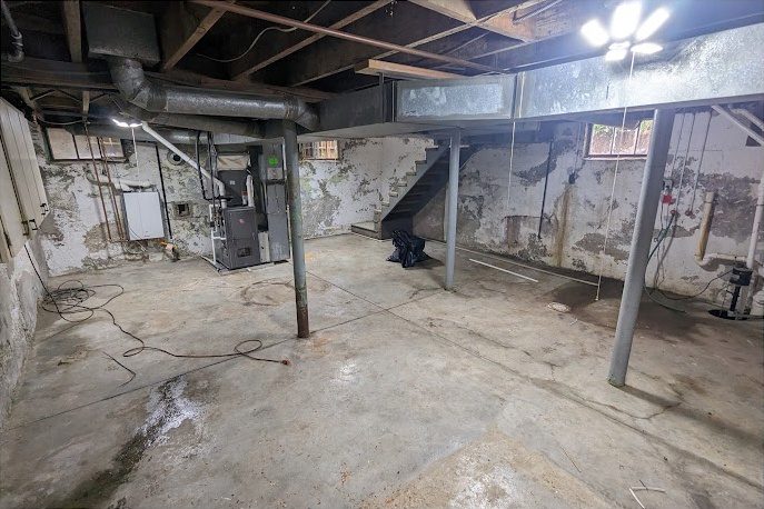 Before: a bare basement with exposed block walls, steel posts and ductwork
