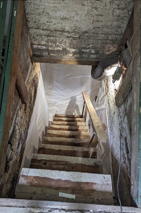 Looking down a cellar stair to white-lined walls at the bottom