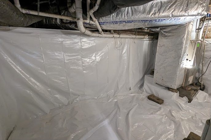 A basement corner with white liner across the walls and floor