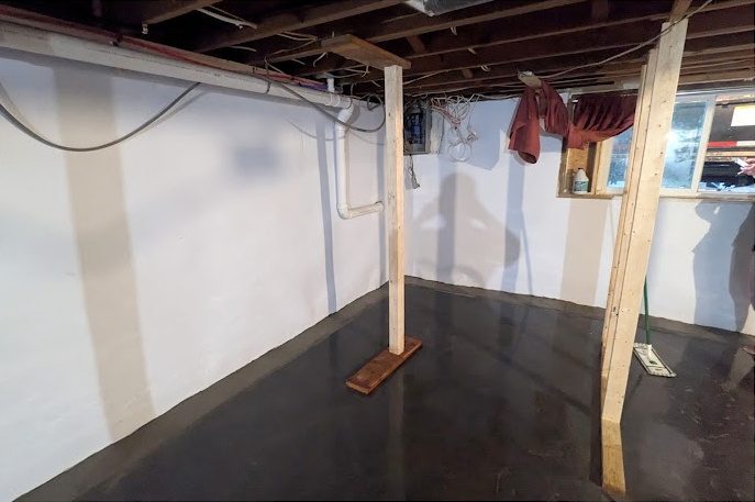 After: the same basement with white-lined walls and timber posts