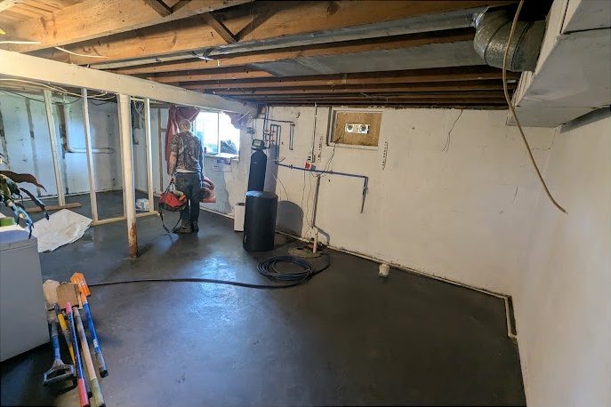 Before: a basement with a water softener and brine tank along the wall