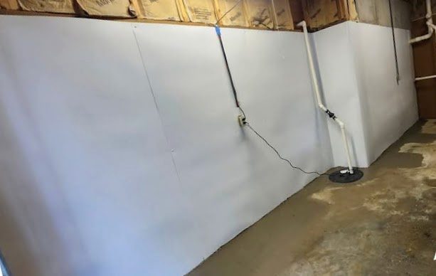 White liner along a basement wall, with the sump at the end of the run