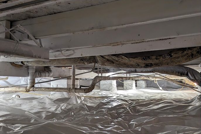 After: the same crawl space with the duct lifted above a clean white liner
