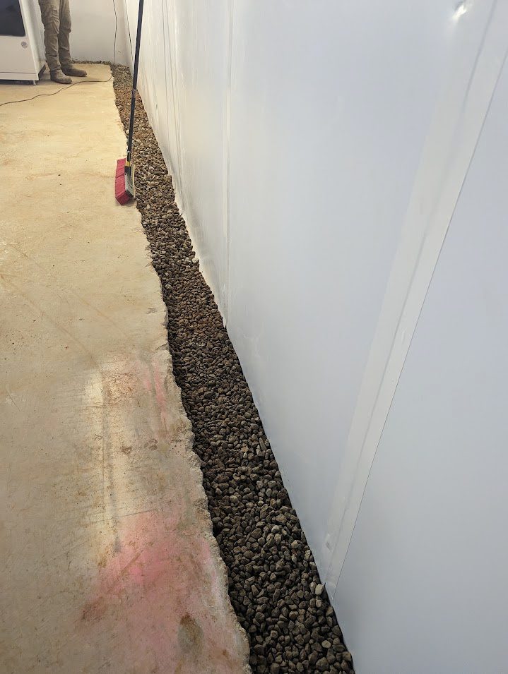 Open gravel perimeter channel beside white wall liner