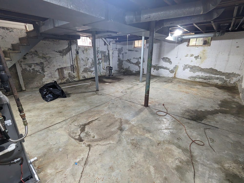 Wide bare basement showing marked masonry walls and posts