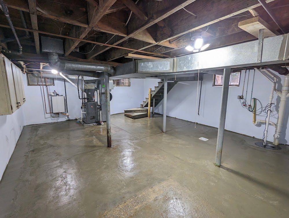 A wide lined basement with the stairs and the sump area