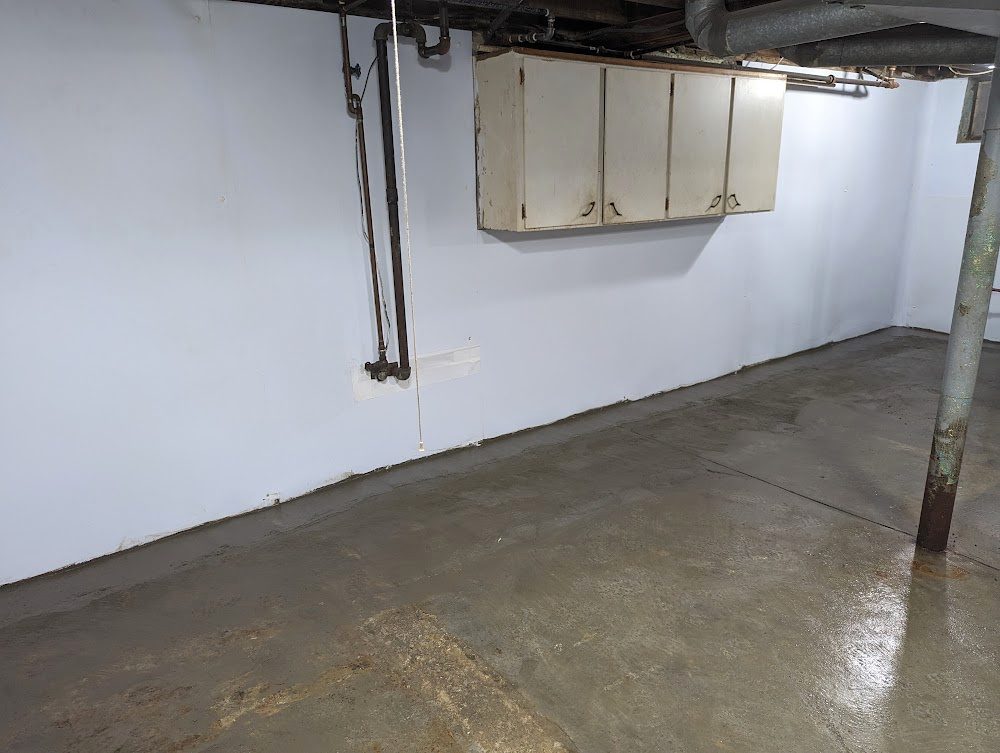 Lined basement wall with utility box and exposed pipes