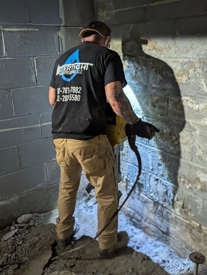 A worker using a demolition hammer on a block wall