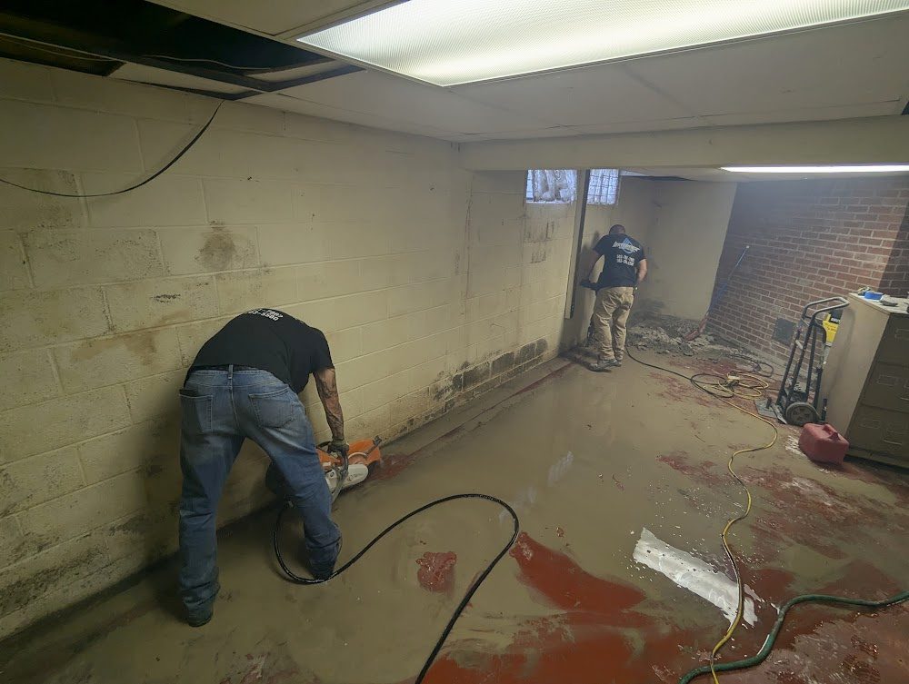 Workers cutting perimeter beside block wall