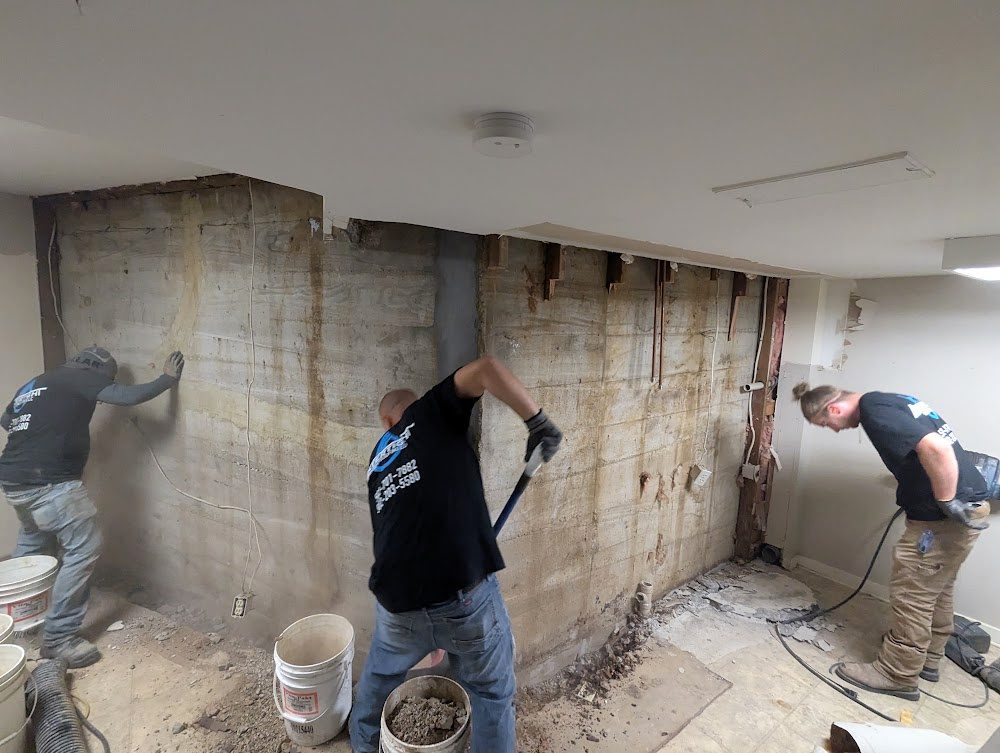 Watertight crew working along an exposed basement foundation wall