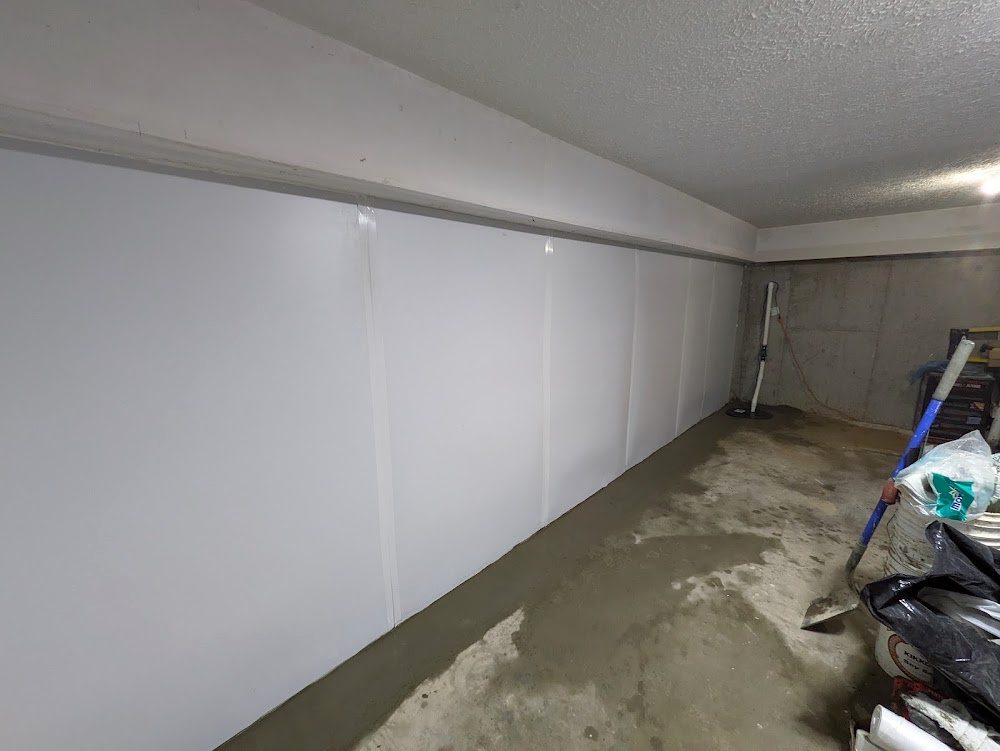 A long white-lined basement wall with a fresh perimeter floor patch