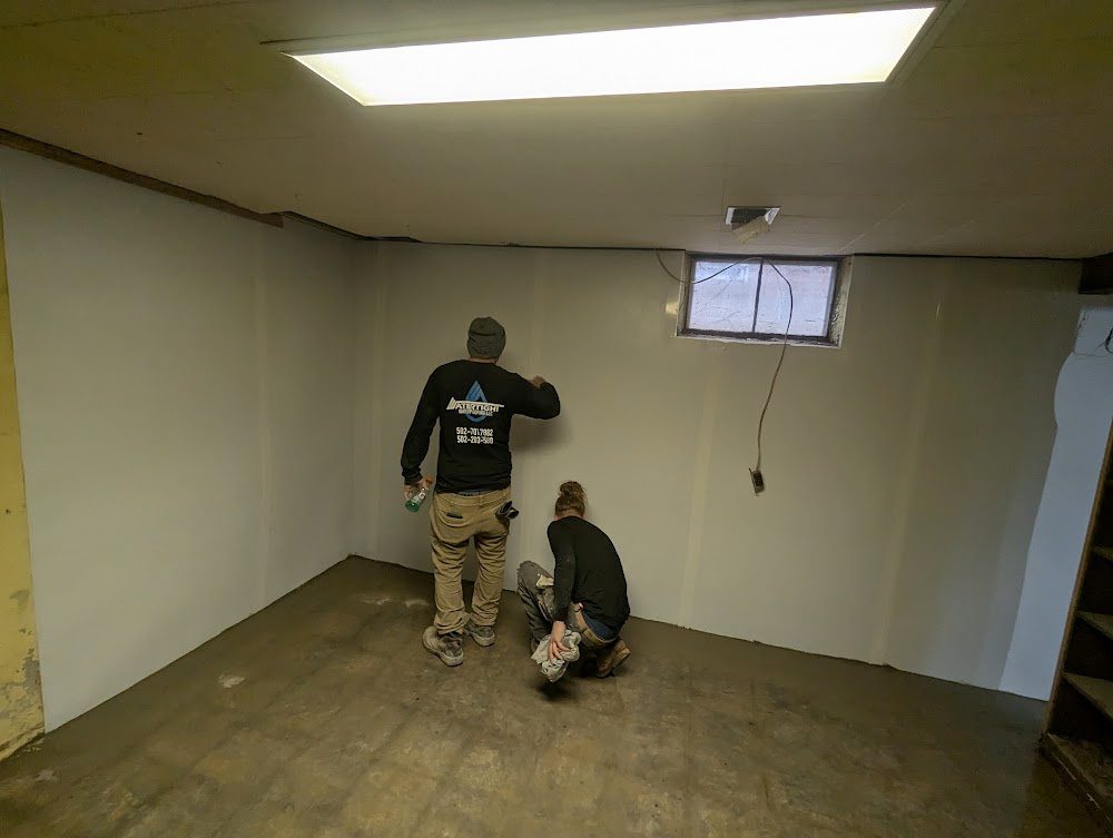 Two workers at lined wall in basement corner