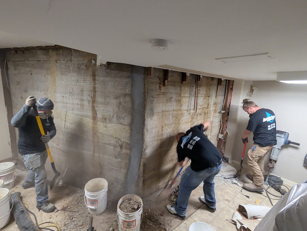 Three workers preparing perimeter along exposed basement wall