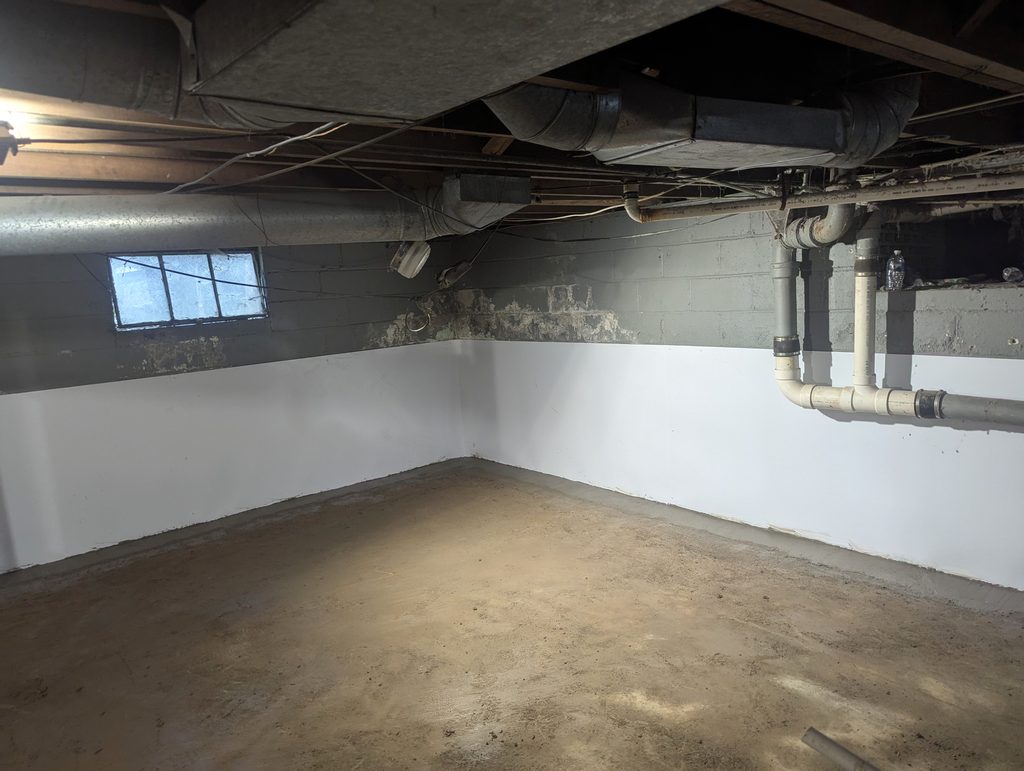 Basement corner with white liner on the lower walls