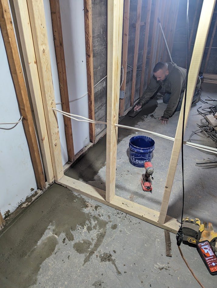 A worker beyond open partition framing, with a fresh floor patch