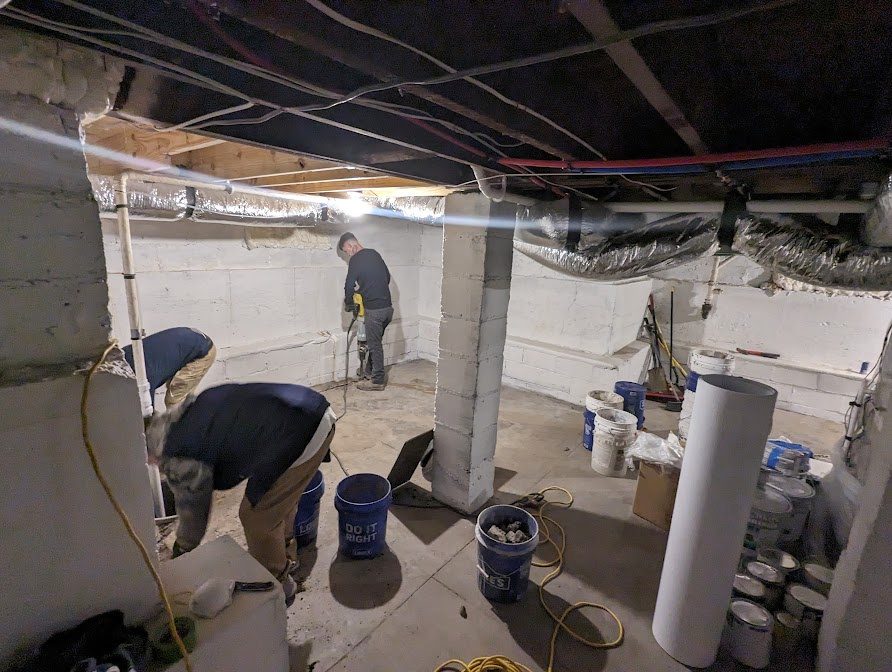 Crew working across a basement, with buckets of materials