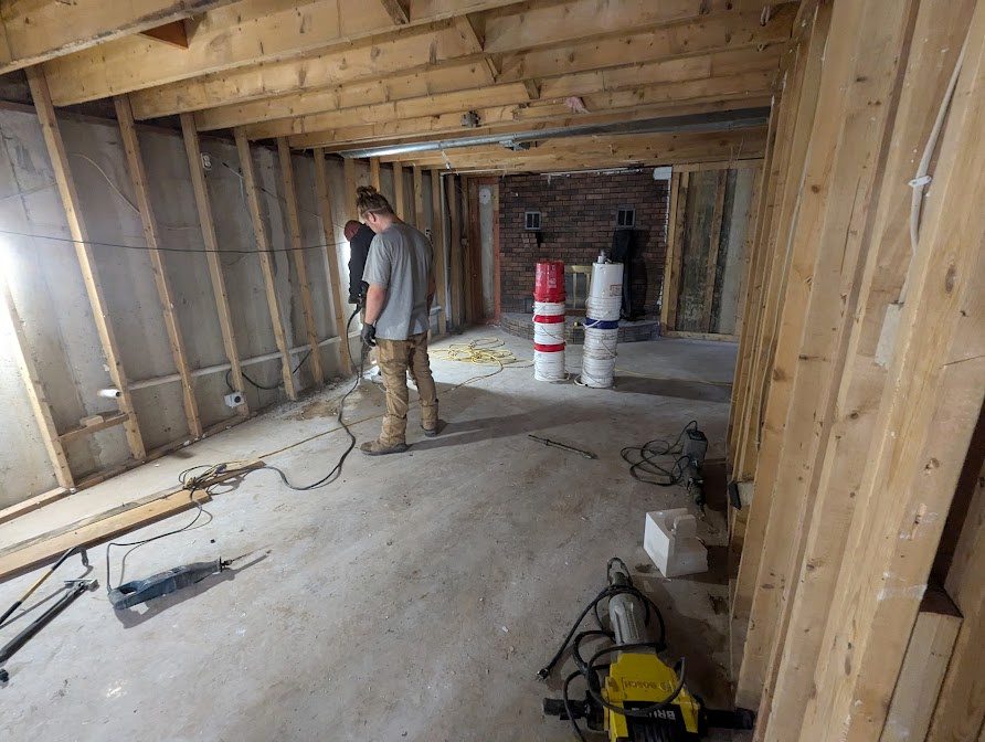 Worker in long basement with opened wall framing