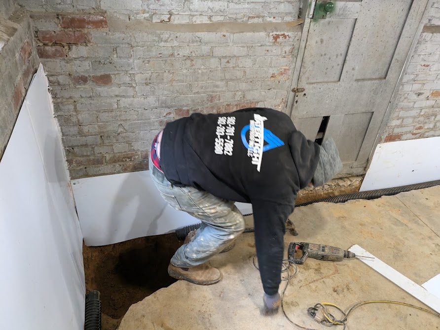Watertight worker fitting white liner beside a basement door