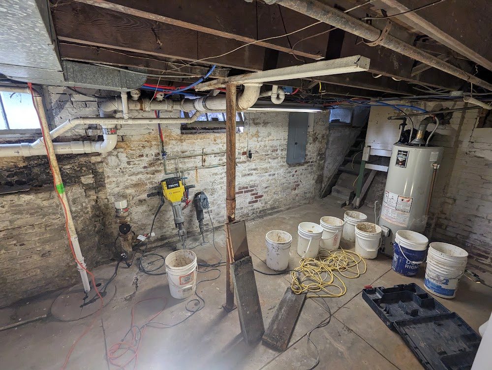 Bare masonry basement work area with buckets