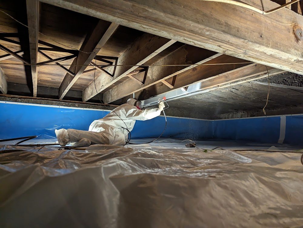 Coveralled worker fitting material beneath exposed joists