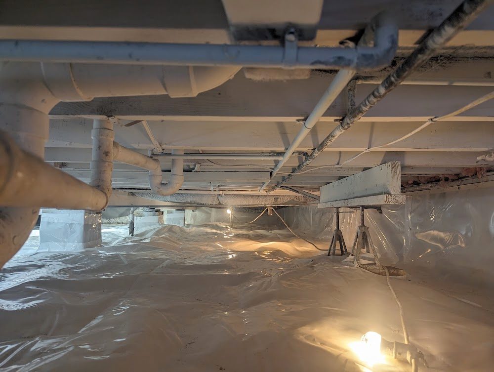 Wide white-lined crawl space with pipes and work lights