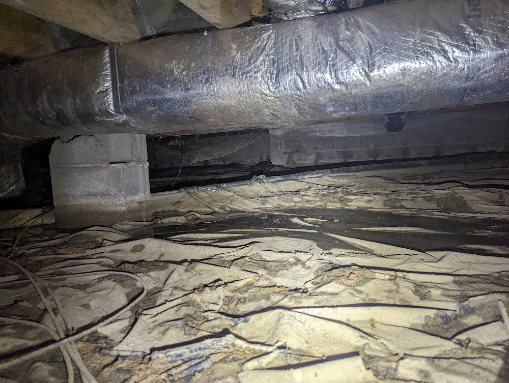 Dark crawl space with old floor sheeting and ducts