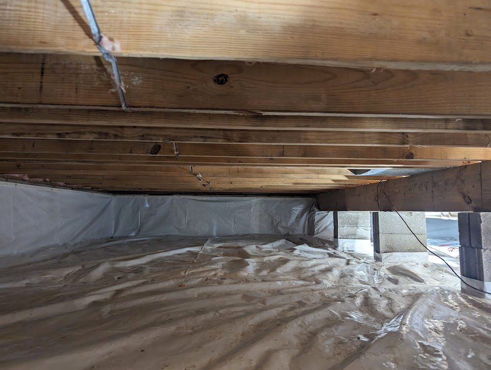 A wide crawl space with clean white wall and floor liner