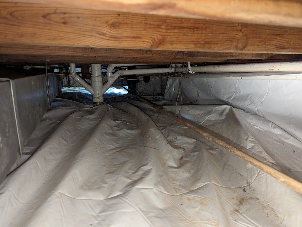 Crawl space with a white liner across the floor and up the perimeter walls
