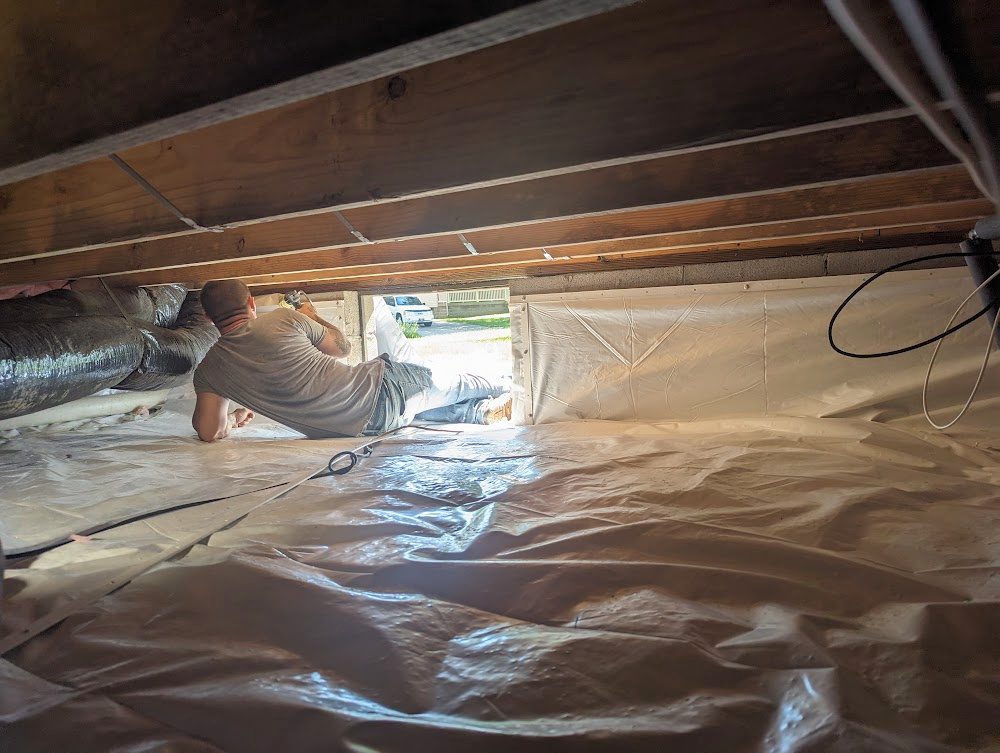Worker at crawl space opening above white liner