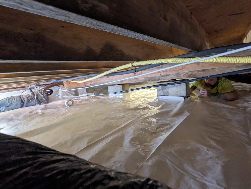 Pipes crossing low over a lined crawl space