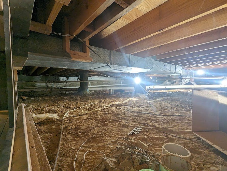 Exposed dirt crawl space with lights and materials