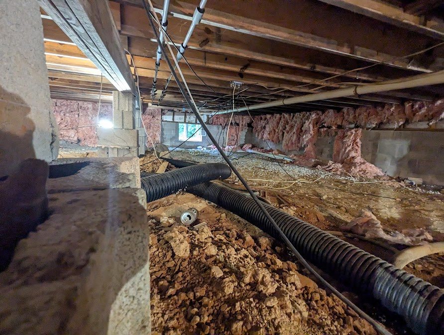 Drainage pipe running along crawl space soil excavation