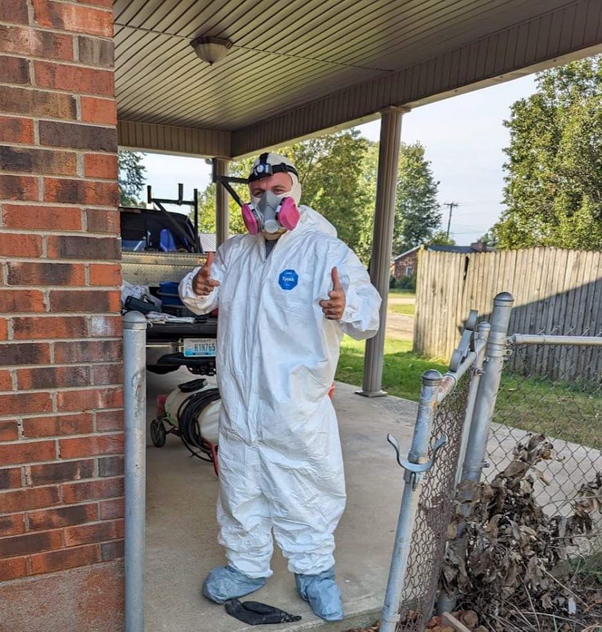 Watertight technician in coveralls and a respirator outside a house
