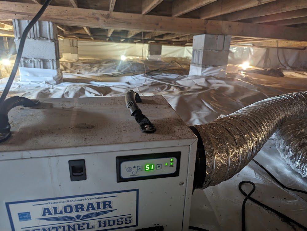 Dehumidifier in foreground of white-lined crawl space