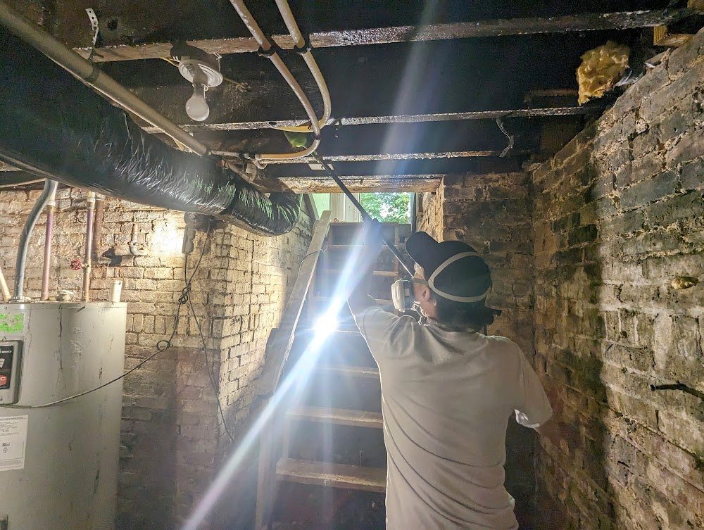 Worker reaching toward overhead surfaces near basement steps