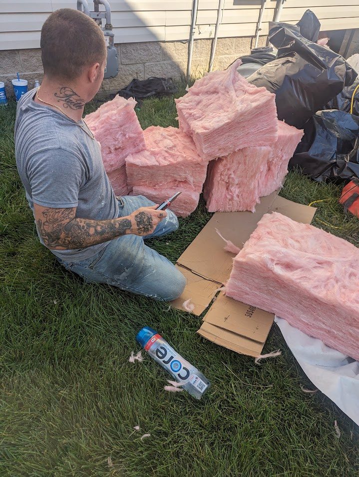 Worker cutting pink insulation outdoors
