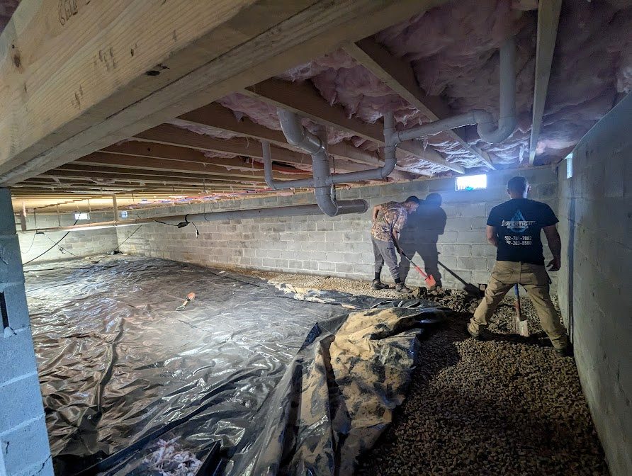 Two workers across crawl space floor with open gravel channel