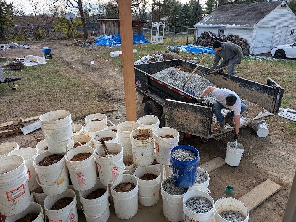 Crew, gravel trailer and buckets beside a house