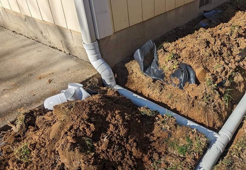 Downspout connected to pipe in open trench