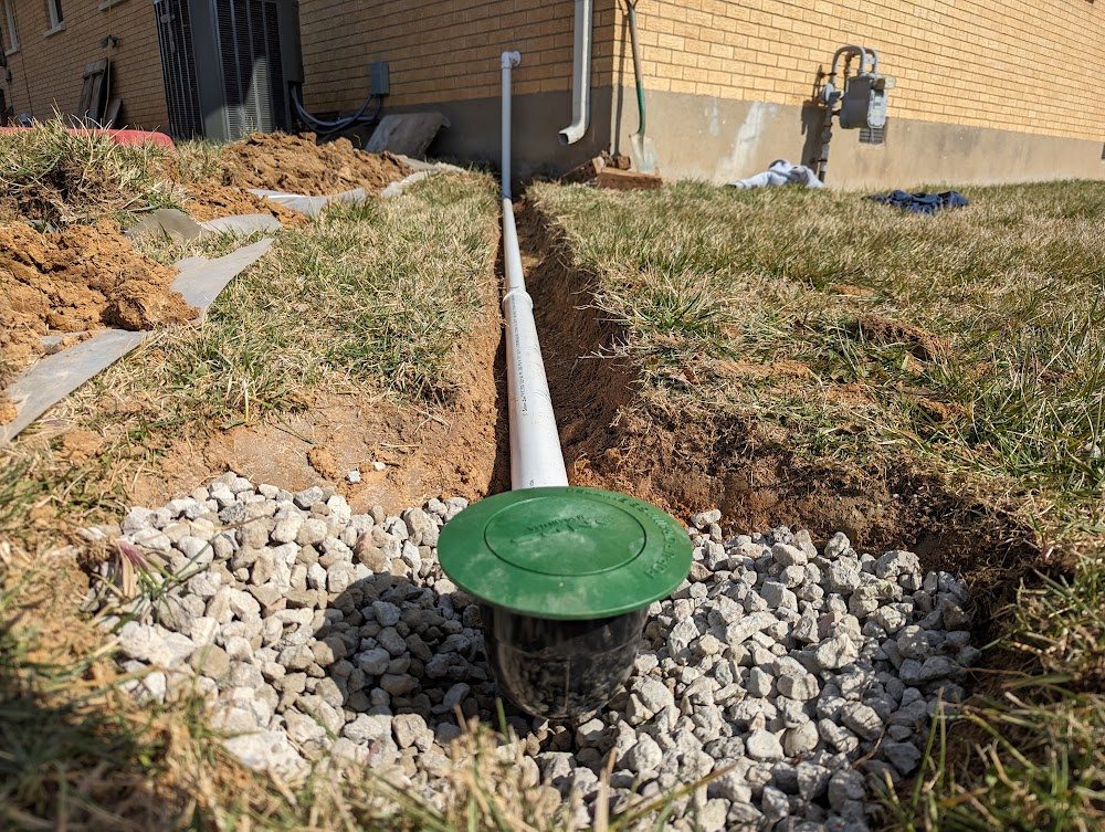 Buried drain pipe and a green emitter in gravel