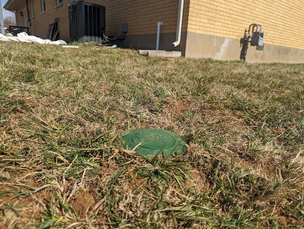 Green drainage emitter in lawn, house beyond