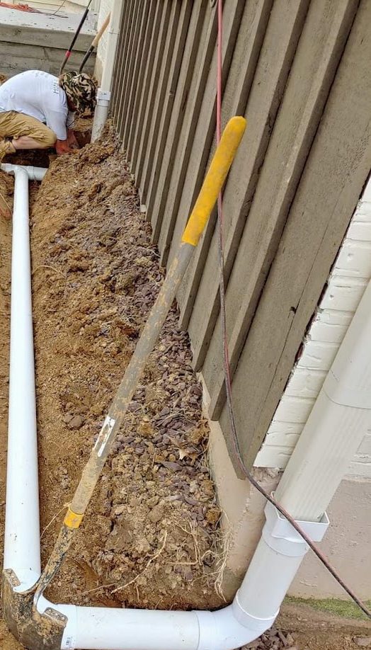 Narrow downspout trench alongside siding