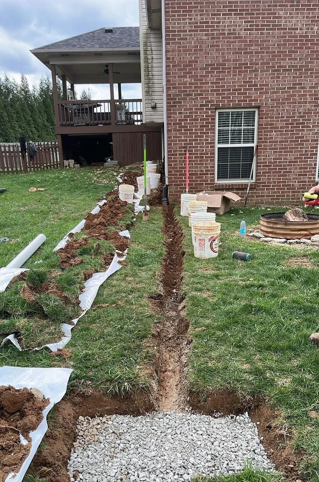 Long trench beside brick home and gravel area