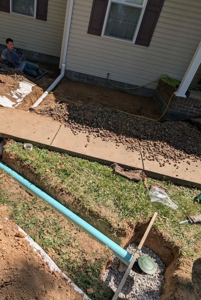 Drainage pipe across trench near siding