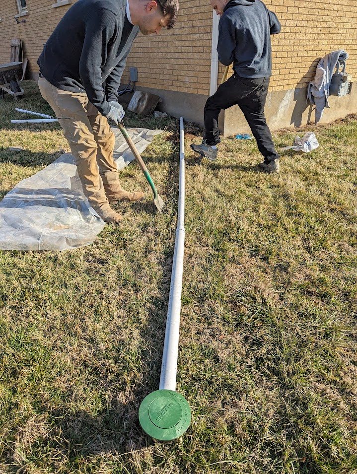 Crew beside a buried drain outlet