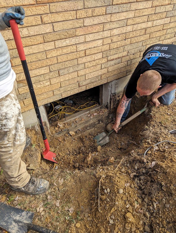 Worker excavating below brick basement window