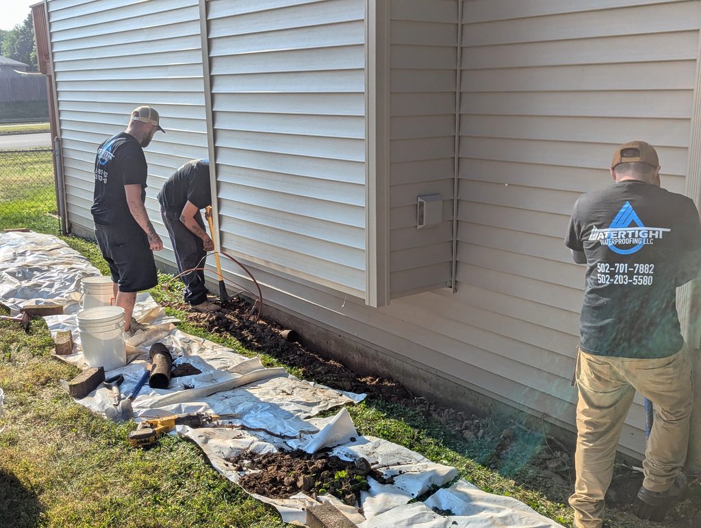 Three crew members beside excavation and siding