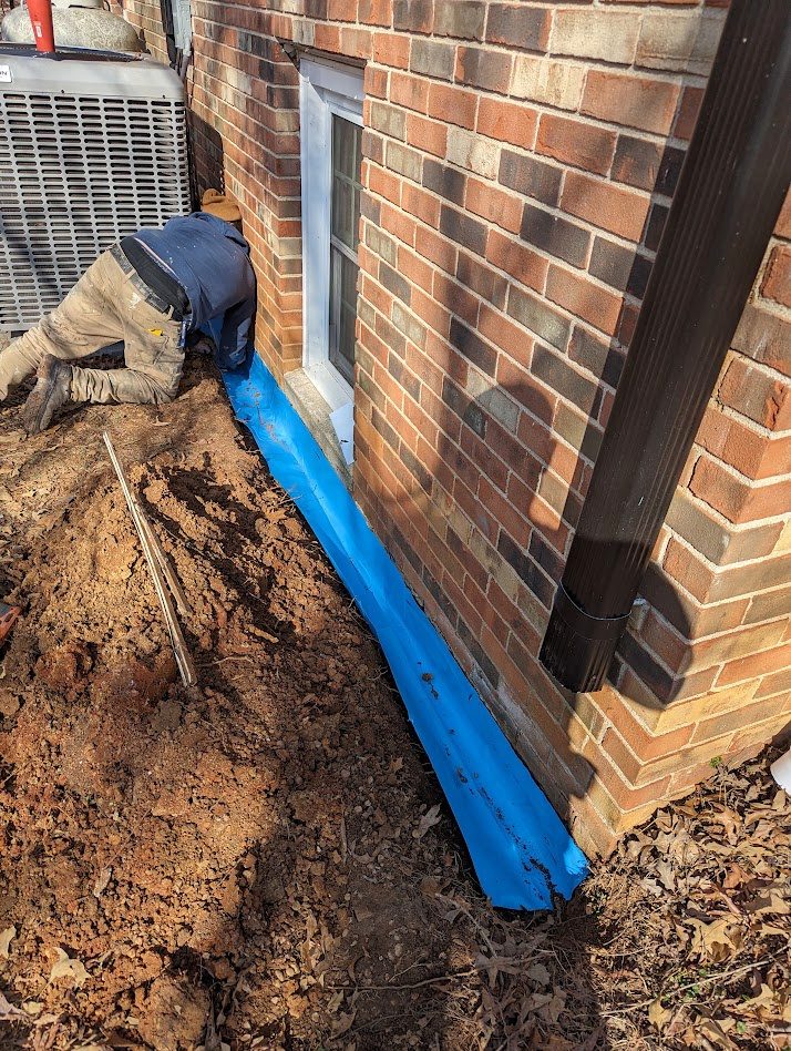 Blue material along brick foundation and worker