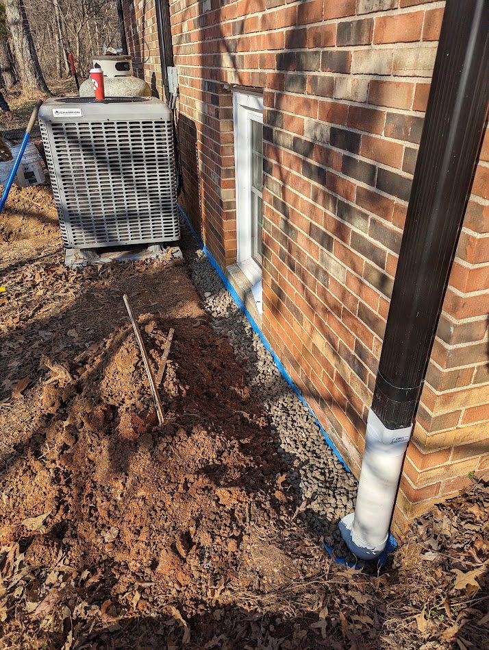 Exposed foundation beside brick wall and downspout